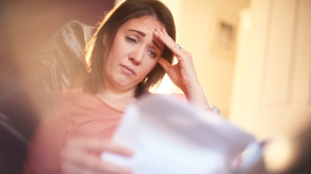 A worried woman holding and reading something on a paper