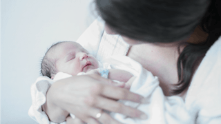 Woman holding her newborn in arms worried about talking postpartum depression