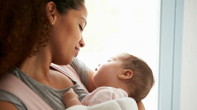 A mother holding her baby and smiling while on her last week of maternity leave