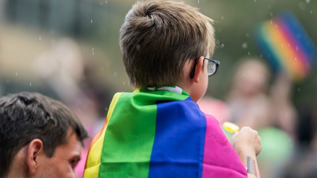 A small kid wearing a rainbow flag over his back representing a trans-kids trend