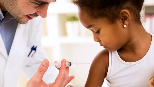 A doctor holding a vaccine injection near a child's arm
