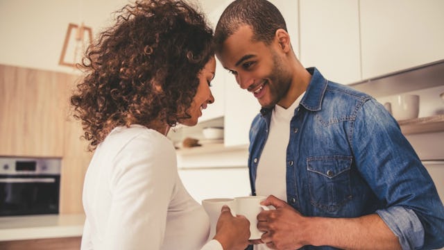 A couple standing head-to-head, holding cups next to each other and the wife is not worried about he...