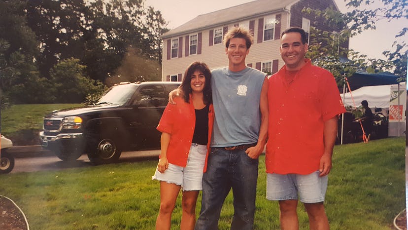 Young Tina Drakakis smiling and wearing an orange shirt while posing for a photo with Ty Pennington 