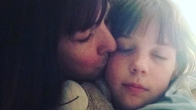 A mother kissing her son while he is sleeping in a selfie