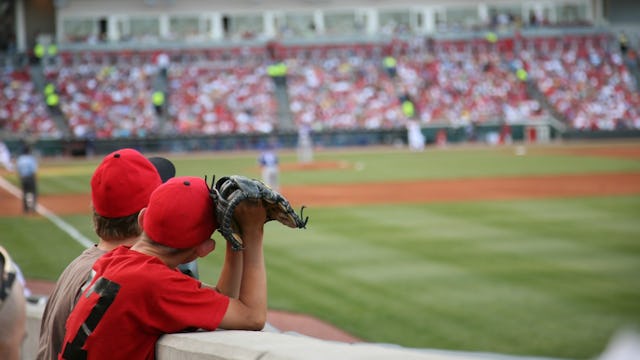 Two young boys looking at a blurred field and full stands during a baseball game