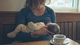 A mom breastfeeding her newborn baby in a coffee shop
