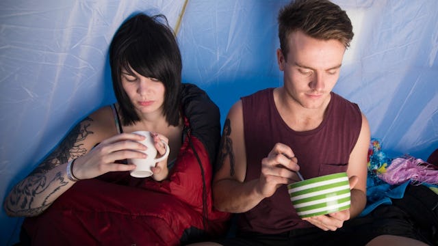 Young couple sitting in a tent while being on a camping trip