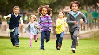 Five happy kids running down a field