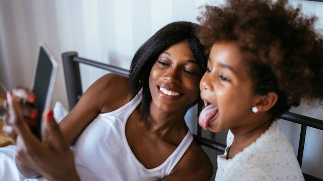 Mother and her daughter posing for a selfie with the mother smiling and her daughter sticking her to...