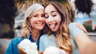 A middle-aged mom with her teenage daughter posing with ice cream