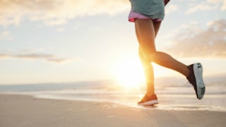 A woman running down a sandy beach in black sneakers whose kids don't always come first