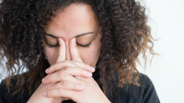 A woman in distress, cradling her head with her clasped hands.
