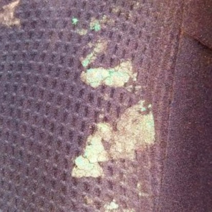 A close-up with stains and scratches on a black couch