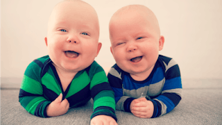 Two twin babies smiling.