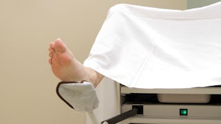 A woman lying in a hospital bed, ready for a gynecologist’s appointment.