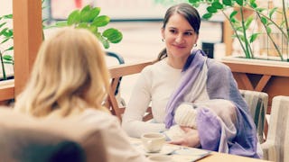 A mother sitting in a restaurant with her baby on her lap