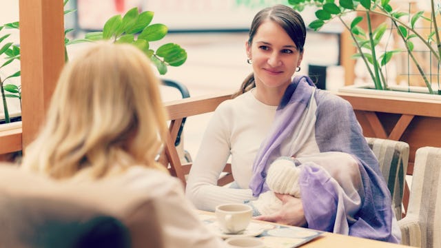 A mother sitting in a restaurant with her baby on her lap