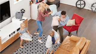 Parents having a pillow fight with their kids in the living room 