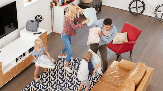 Parents having a pillow fight with their kids in the living room