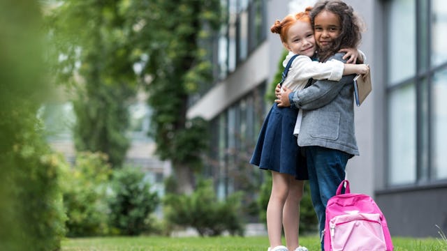 Two BFF girls hugging in front of the school