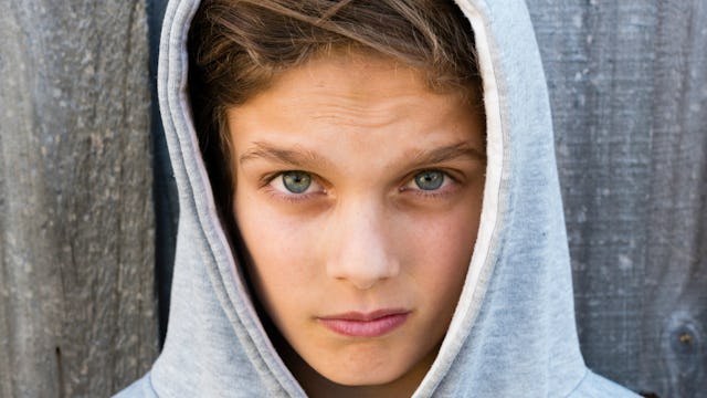 A moody teenager with blue eyes in a hoodie