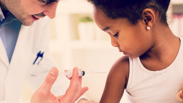 A doctor holding a vaccine injection next to a girl's arm