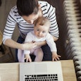 A mother working at home on her laptop while holding her baby on her lap