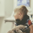A blonde toddler diagnosed with a Pediatric Brain Tumor holding a plush toy in a hospital bed.