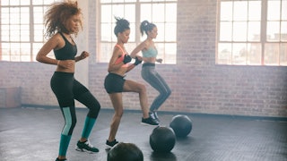 Three women at the training and doing jumping jacks in a gym