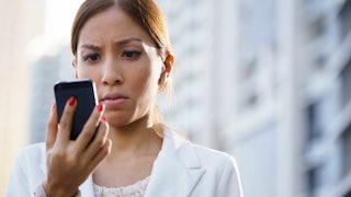 An angry woman looking at the upsetting text message on her phone screen