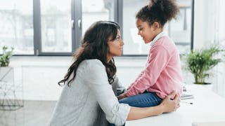 A woman effectively talking to her kid who's sitting on a desk