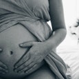 Black and white image of a woman pregnant with twins holding her belly