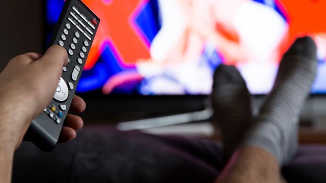 Man holding a remote control and watching TV