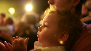 A close-up of a mom holding her baby in a crowded place in her arms while she's dealing with social ...