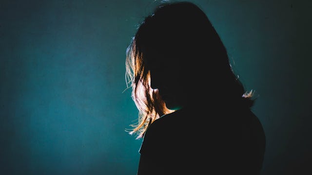A woman that suffers from anhedonia standing alone in a dark room