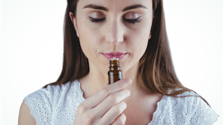 A woman calmly smelling essential oil