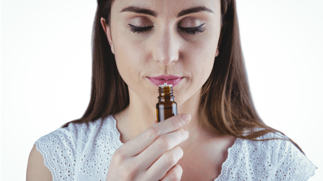 A woman calmly smelling essential oil 