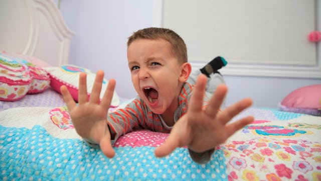 A boy yelling while lying on a bed and behaving like a brat