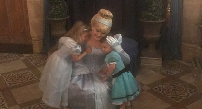 A girl and her brother, both wearing dresses while hugging a woman dressed as Cinderella