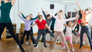 A boy with autism and six of his friends at a gymnastics birthday party doing exercises with the ins...