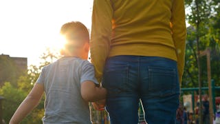 A mother in a yellow sweater and blue denim jeans who keeps her kid safe from abuse holding her son'...