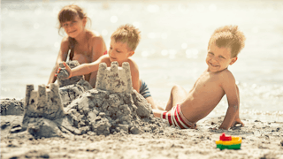 Three children at a beach playing and making sand castles