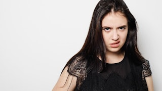 Teenage girl wearing a black shirt, looking straight ahead with an angry face and lifted eyebrow