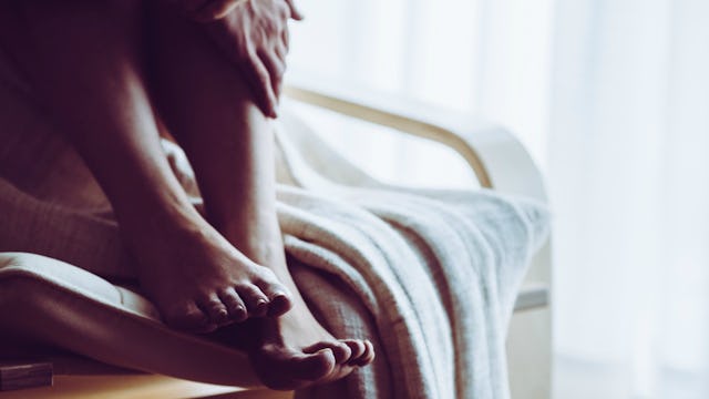 A victim of gaslighting with her legs curled up and on the edge of a bed