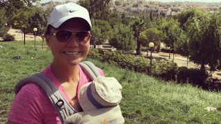 An introverted SAHM mum holding her baby in a front backpack while on a nature hike.