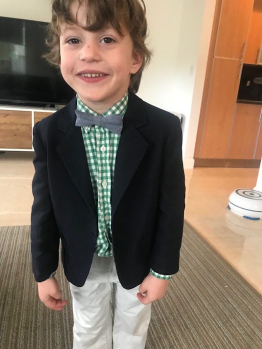 A young boy in a suit smiling and posing in a living room