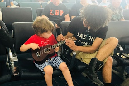 A father showing a little son how to play the guitar.