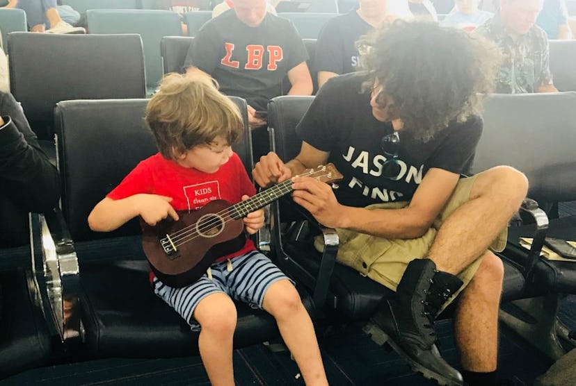 A father showing a little son how to play the guitar.