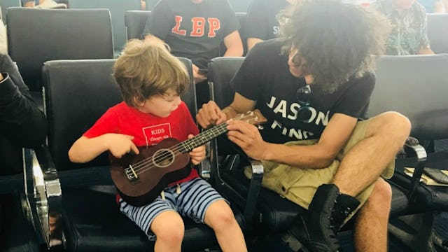 A father showing a little son how to play the guitar.