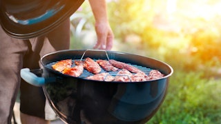 A man grilling chicken fillets on an outdoor BBQ grill